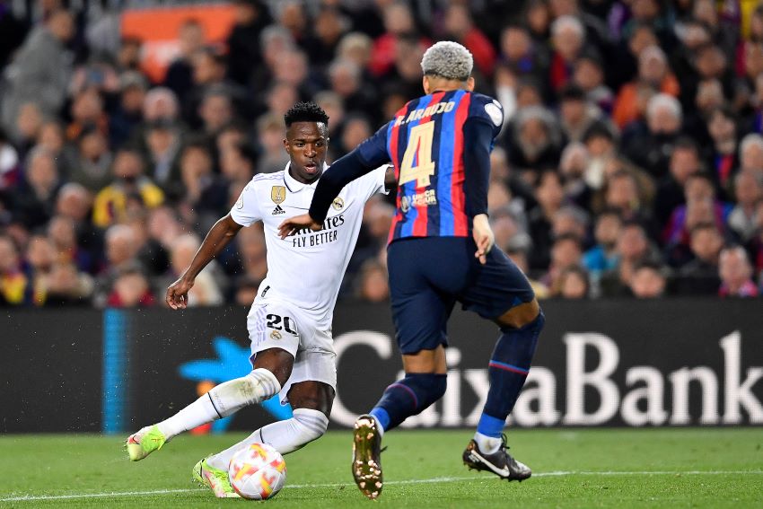 Wide attacker Real Madrid Vinicius Junior melewati kawalan bek kanan FC Barcelona Ronald Araujo di Camp Nou (6/4). - Image