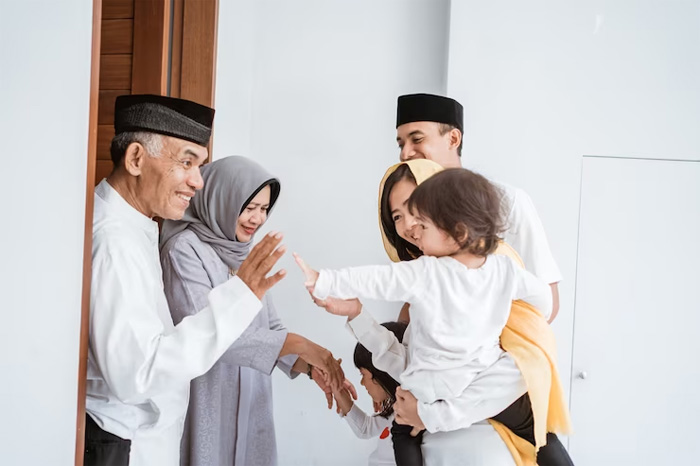 Pasangan usia muslim asia yang bahagia bertemu dengan anak-anak dan cucu di depan pintu selama perayaan  Idul Fitri. (Foto: Freepik.com)