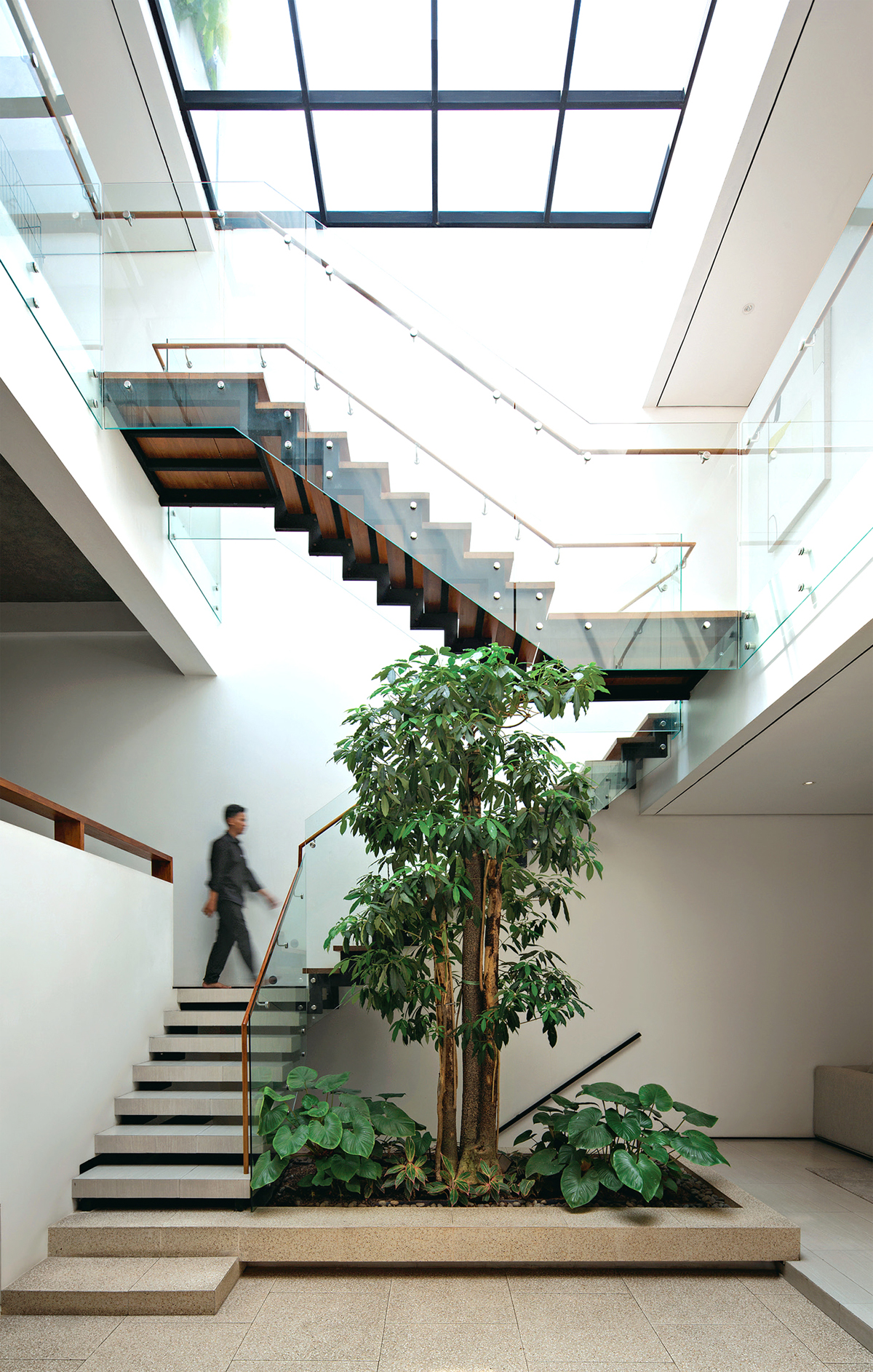 VISUAL DAN FUNGSI: Selain menghasilkan estetis, desain tangga dengan railing kaca pada inner courtyard juga berfungsi sebagai akses pencahayaan.
