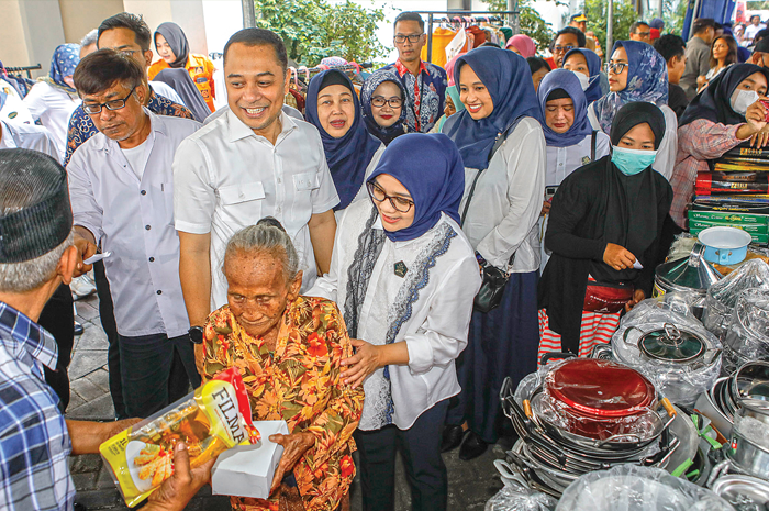 SEDIAKAN BARANG MURAH: Wali Kota Surabaya Eri Cahyadi bersama Gerakan Organisasi Wanita Surabaya Rini Indriyani membantu warga membeli barang di event garage sale. - Image