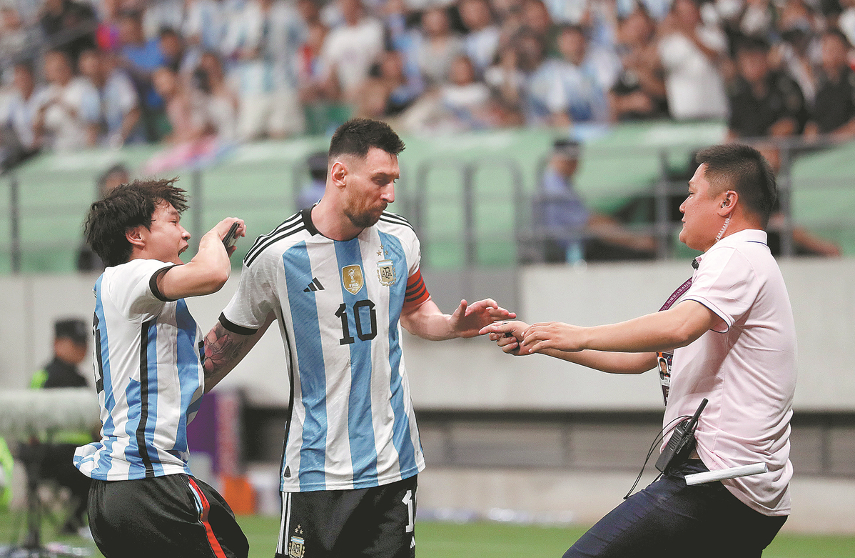 Penggemar berat Lionel Messi hendak diamankan petugas keamanan usai memeluk idolanya tersebut. Dia ditahan dan dilarang masuk stadion selama 1 tahun. - Image