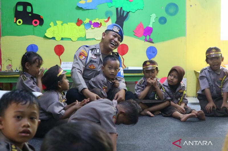 Anggota Subbid Provos Bidpropam Polda DIJ sekaligus pendiri TK Bumi Damai Indonesia, Bripka Heri Prasetyo bermain bersama murid TK itu di Dusun Krambil, Desa Girisekar, Kec. Panggang, Gunungkidul. - Image