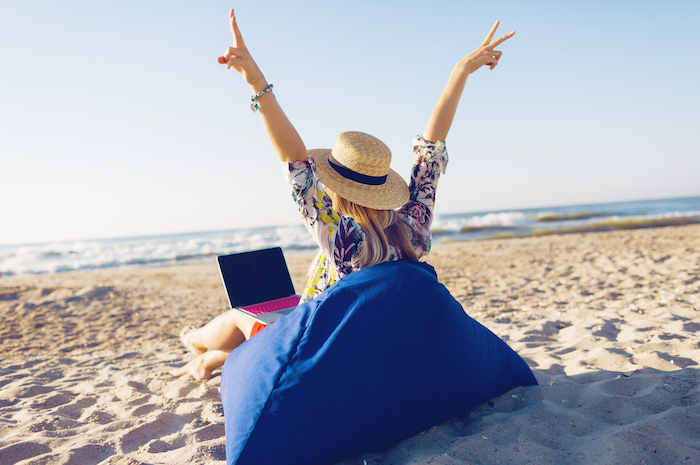 Perempuan yang sedang bekerja dengan laptopnya di pantai. (svetlanasokolova/Freepik) - Image
