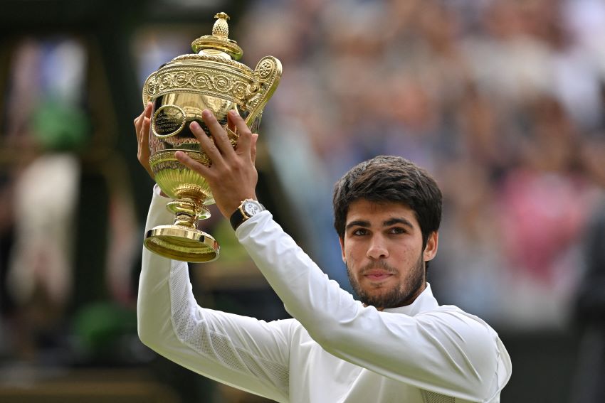 Carlos Alcaraz mengangkat trofi Wimbledon usai mengalahkan Novak Djokovic di final. - Image