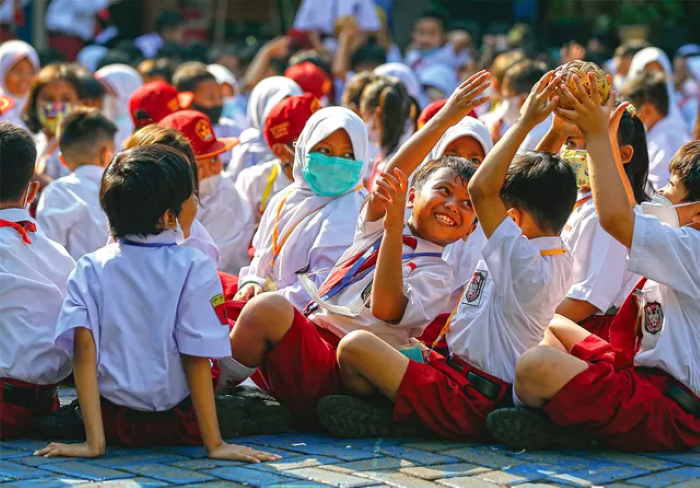 Siswa SDN Ketabang 1 Surabaya memainkan bola bersama rekan-rekannya sebelum memasuki ruang kelas pada hari pertama masuk sekolah (17/7). - Image