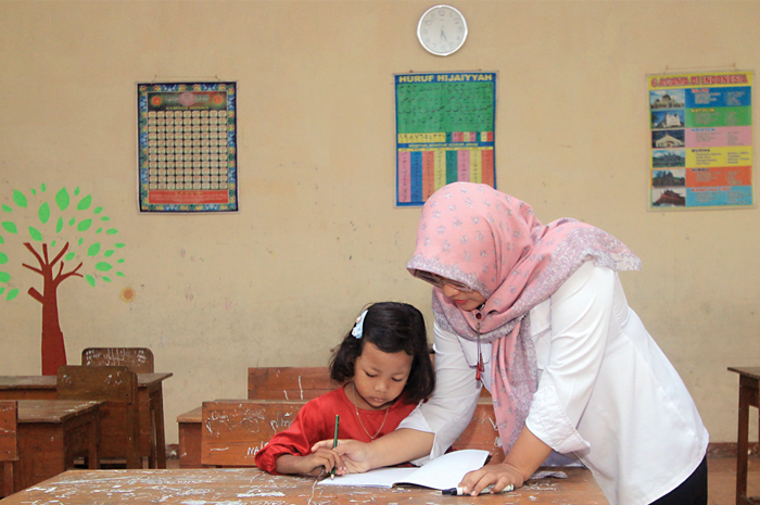 MINIM SISWA: Fahira Bunga Formoza, satu-satunya siswa baru di SDN 1 Setono, didampingi seorang guru kelas I pada hari perdana sekolah, Senin (17/7). - Image