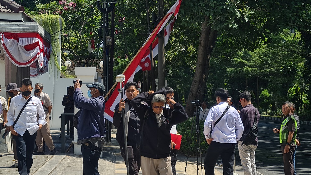 Petugas mengukur tinggi tembok depan Gedung Wismilak Surabaya. - Image