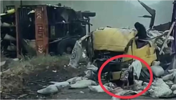 Balita korban kecelakaan merangkak keluar dari puing-puing truk yang ringsek. - Image