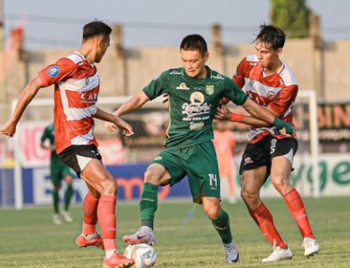 Sho Yamamoto (tengah) diapit dua pemain Madura United di Stadion Bangkalan, Minggu (17/9). Persebaya kandas 3-0 di pertandingan tersebut. (twitter persebaya) - Image