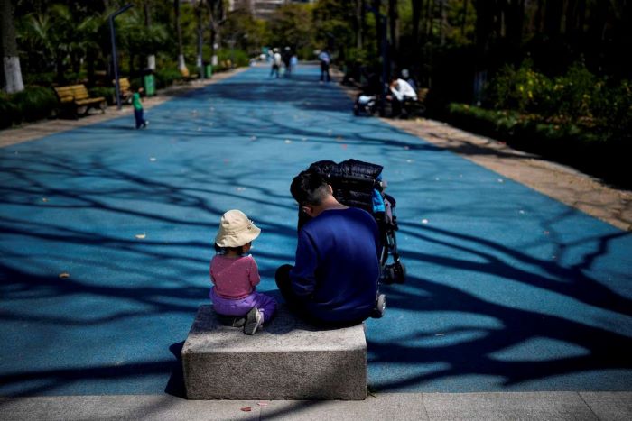 Seorang gadis tengah duduk bersama ayahnya di sebuah taman di Shanghai, Tiongkok. - Image