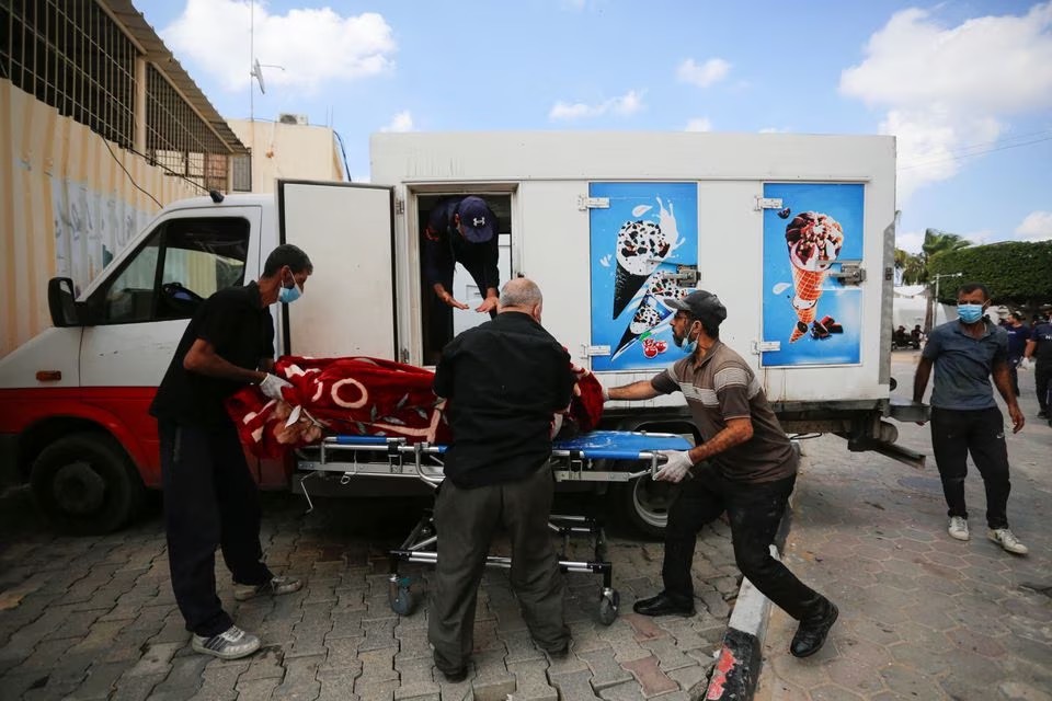 Orang membawa mayat seorang warga Palestina yang terbunuh dalam serangan Israel, dari sebuah truk es krim./REUTERS/Stringer. - Image