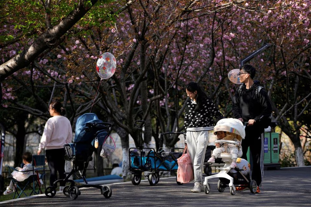 Tampak seorang orang tua bersama anak mereka berjalan-jalan di sebuah taman di Shanghai, Tiongkok pada 2 April 2023. (Sumber: REUTERS/Aly Song) - Image