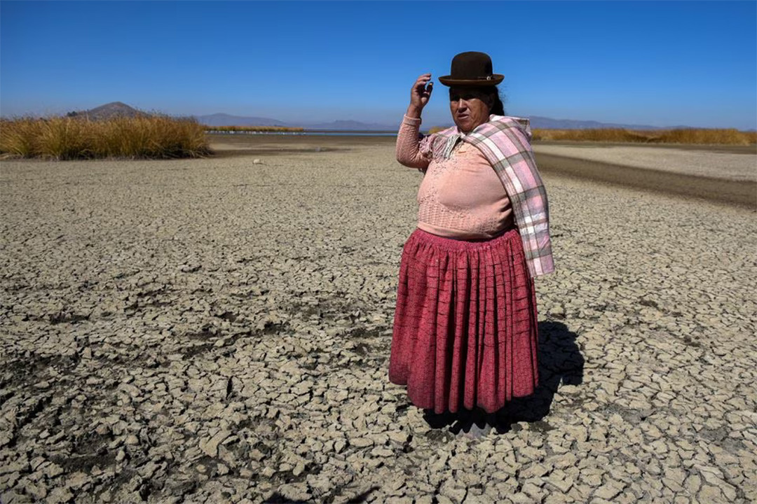 Seorang perempuan di Bolivia menunjukkan kawasan Danau Titicaca yang kering tanpa air selama musim kemarau pada Jumat (3/11). - Image