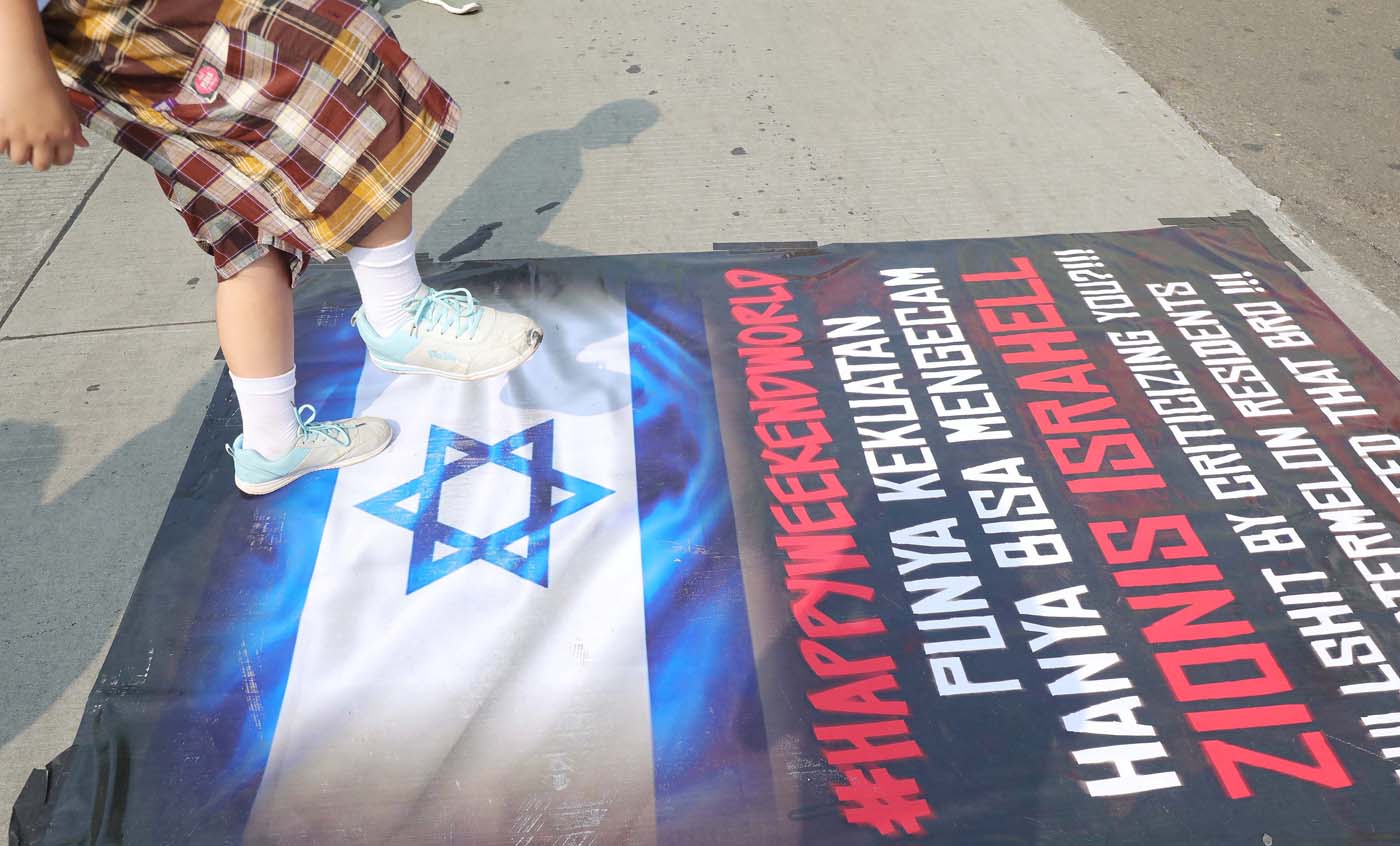 Masyarakat menginjak spanduk yang terdapat bendera Israel di Car Free Day, Jakarta, Minggu (12/11/2023). Kegiatan ini sebagai bentuk kecaman terhadap serangan Israel terhadap Palestina. - Image