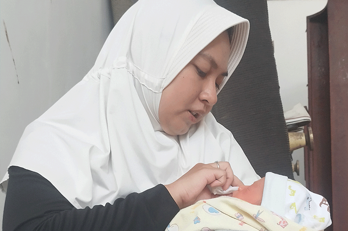 DIRAWAT NAKES: Dokter Gita Syahputri menyeka wajah bayi yang dia temukan di Jalan Manyar Tirtoyoso Jumat (10/11) lalu. Untuk sementara, dia merawat bayi itu. - Image