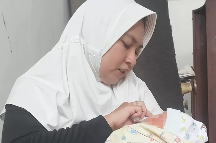 DIRAWAT NAKES: Dokter Gita Syahputri menyeka wajah bayi yang dia temukan di Jalan Manyar Tirtoyoso Jumat (10/11) lalu. Untuk sementara, dia merawat bayi itu. - Image