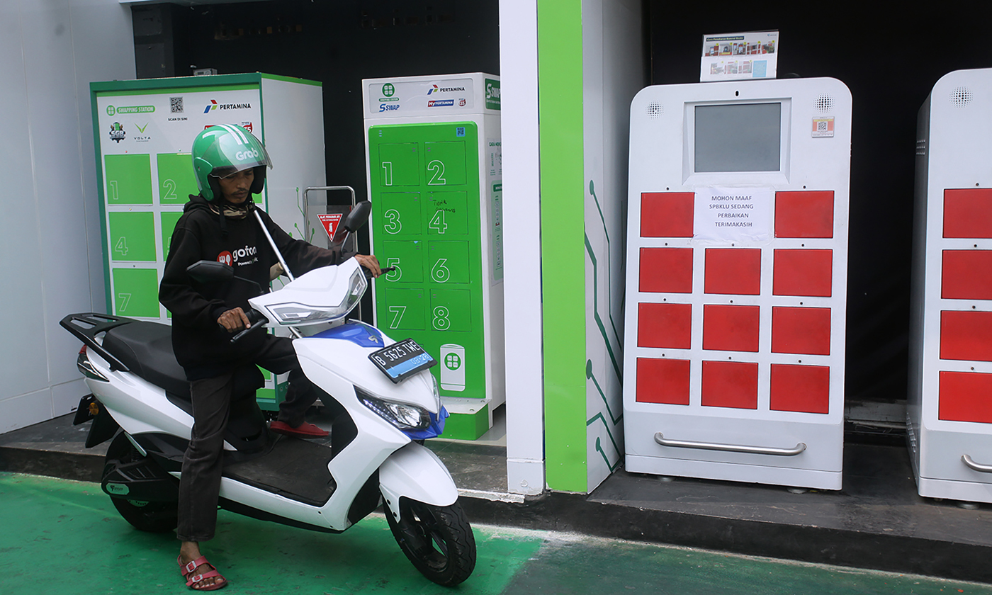 Seorang pengemudi ojek online menukar baterai (swap) sepeda motor listrik dengan yang sudah penuh terisi di Stasiun Penukaran Baterai Kendaraan Listrik Umum (SPBKLU) di SPBU Pertamina, Jakarta.