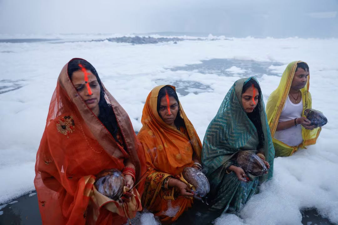 Beberapa umat Hindu di India ketika merayakan festival keagamaan Hindu, Chhath Puja di Sungai Yamuna yang tengah diselimuti buih pada Senin (20/11). (Sumber: REUTERS/Anushree Fadnavis) - Image