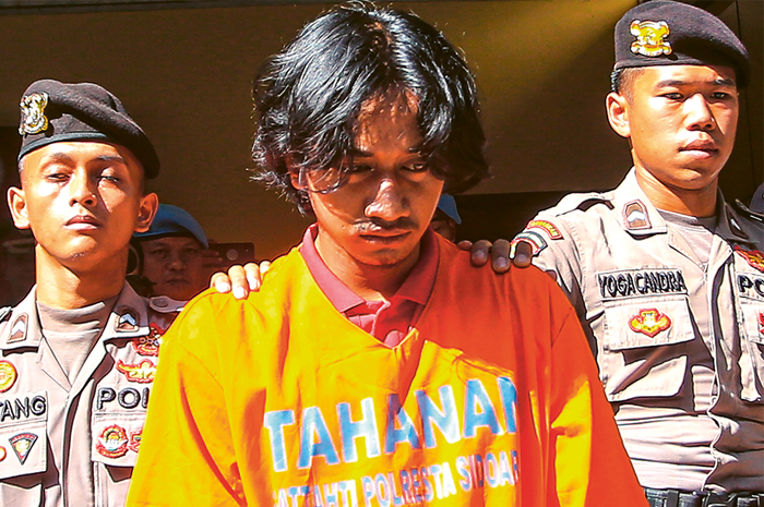 PERUSAK MASA DEPAN: Azali, salah seorang tersangka rudapaksa, digelandang petugas saat gelar perkara di Mapolresta Sidoarjo kemarin (20/11). Akibat perbuatannya, pelaku diancam 15 tahun penjara. - Image