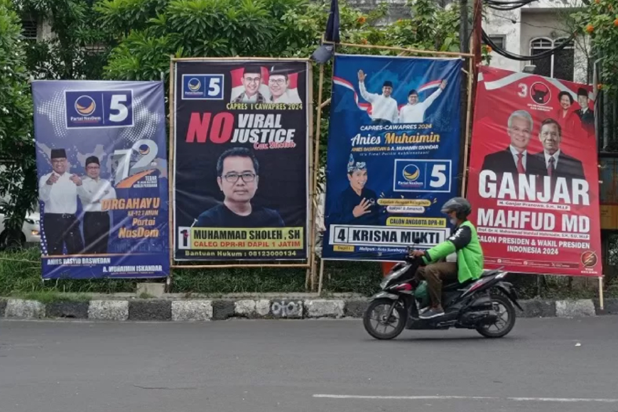 Pengendara motor melintas tak jauh dari alat peraga kampanye yang terpasang di Jalan Kapasan, Surabaya. (Radar Surabaya/Suryanto) - Image