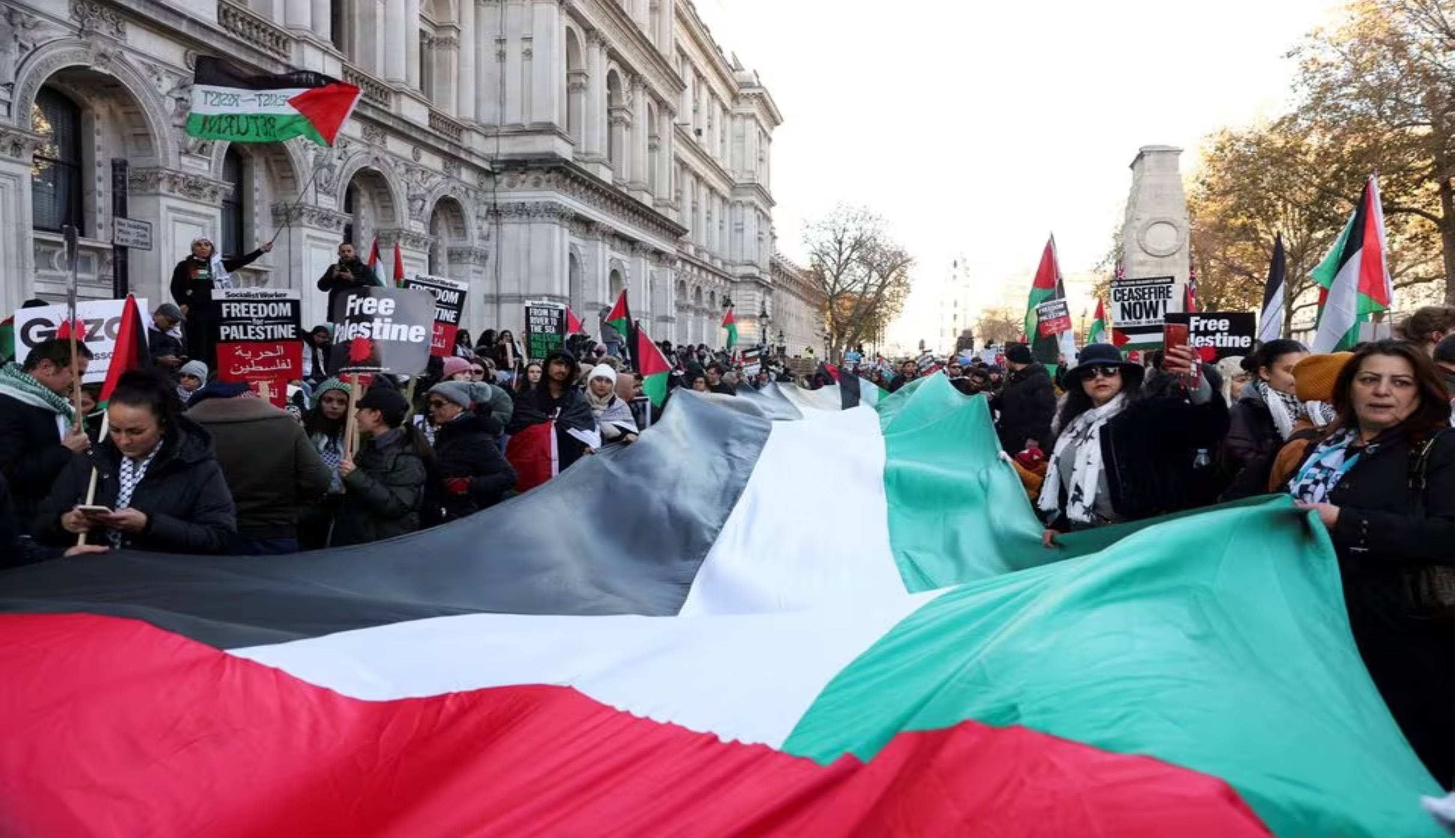 Demonstran mengibarkan bendera Palestina dan membentangkan tulisan untuk Gaza di pusat Kota Londo pada Sabtu (25/11) waktu setempat (Hollie Adams/Reuters) - Image