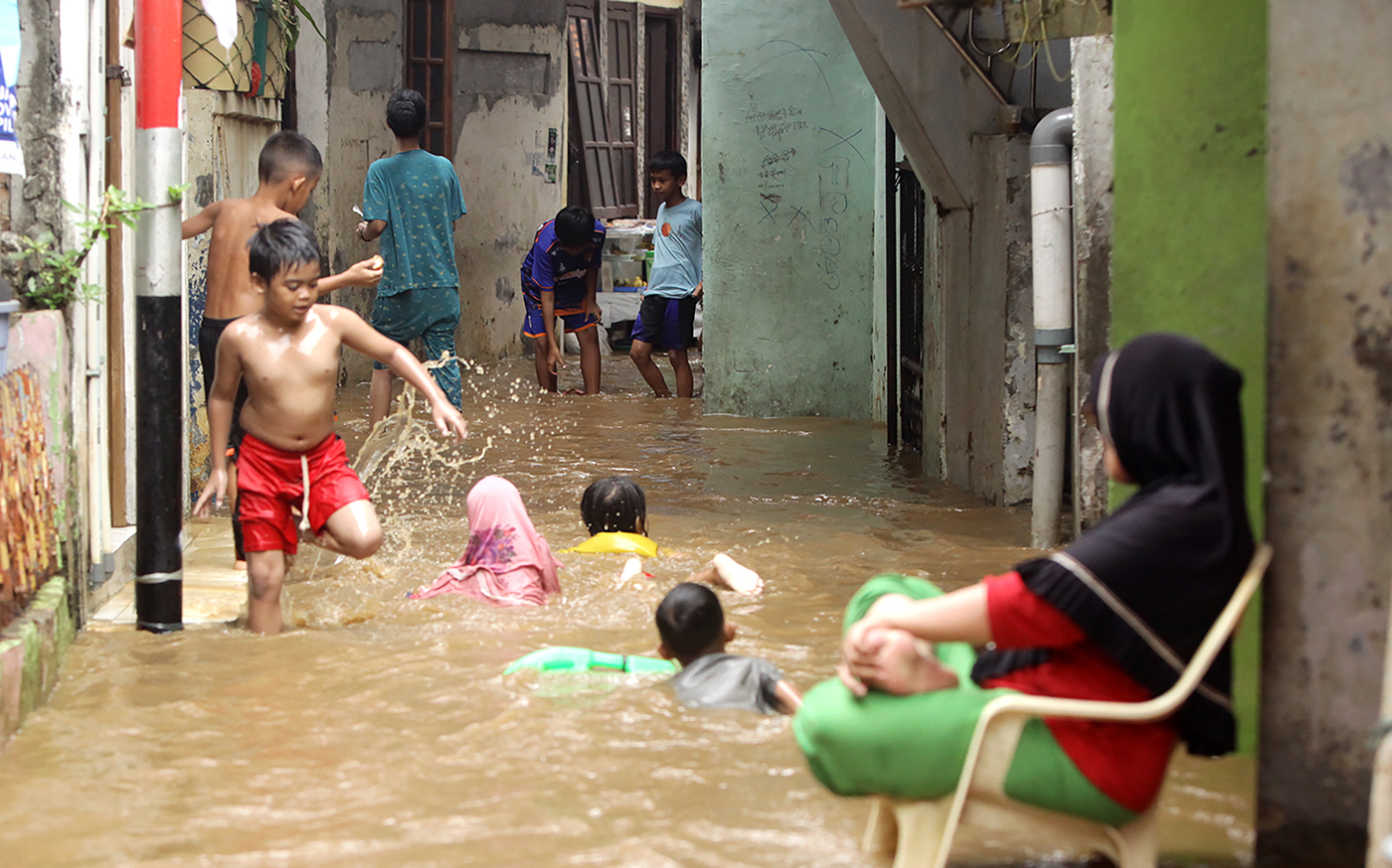 Anak-anak bermain di tengah banjir yang menggenang terendam banjir di Kebon Pala, Kelurahan Kampung Melayu, Jatinegara, Jakarta Timur, Kamis. (30/11/2023). - Image