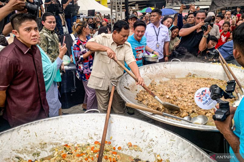 Capres nomor urut 2 Prabowo Subianto (tengah) didampingi konten kreator Bobon Santoso mengaduk masakan saat acara Makan Besar bersama di Cilincing, Jakarta Utara. - Image