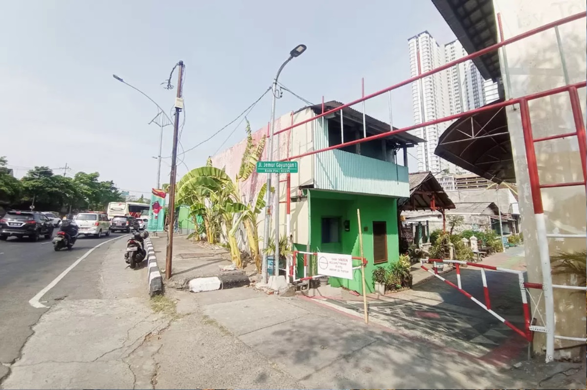 Pengendara melintas tak jauh dari permukiman yang terimbas pembangunan underpass Taman Pelangi, Surabaya. (FOTO: SURYANTO/RADAR SURABAYA) - Image