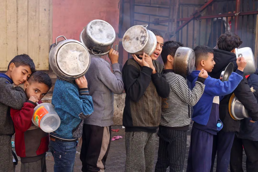 Anak-anak Palestina sedang mengantre makanan dengan panci yang mereka bawa di tengah kekurangan persediaan makanan. - Image