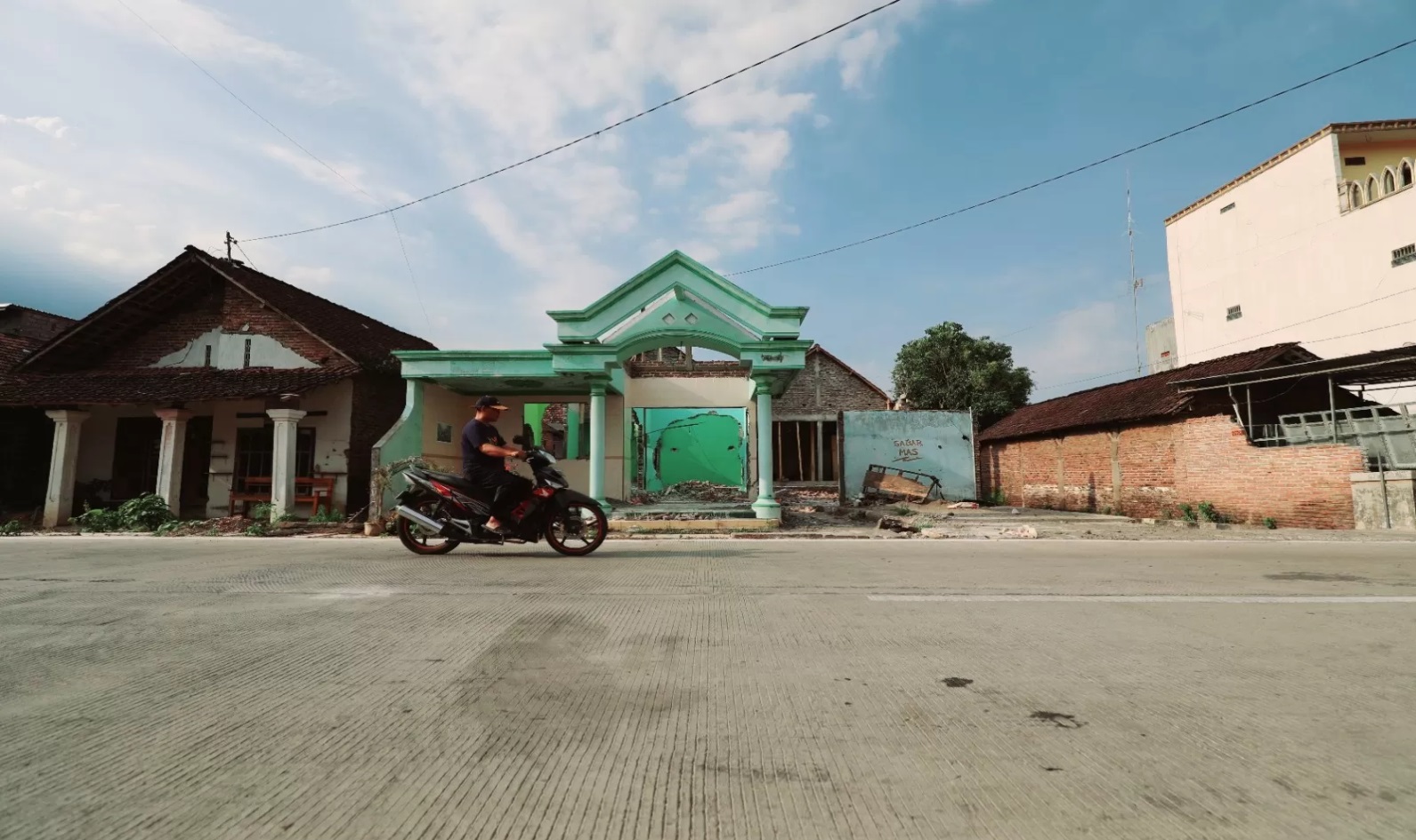 Pengendara sepeda motor melintas di depan rumah warga Desa Tiron, Kecamatan Banyakan, yang sudah dibongkar. (Foto: Wahyu Adji/JPRK) - Image