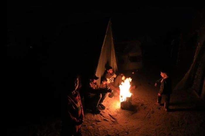 Pengungsi Palestina di tengah api unggun di tempat penampungan sementara di kota Rafah, Jalur Gaza selatan, pada 18 Desember 2023 - Image
