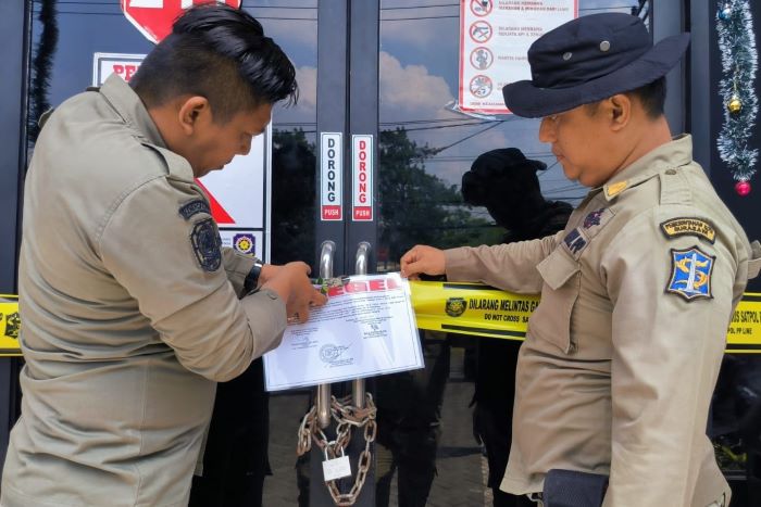 Petugas Satpol PP Kota Surabaya melakukan penyegelan salah satu bangunan unit usaha RHU. - Image