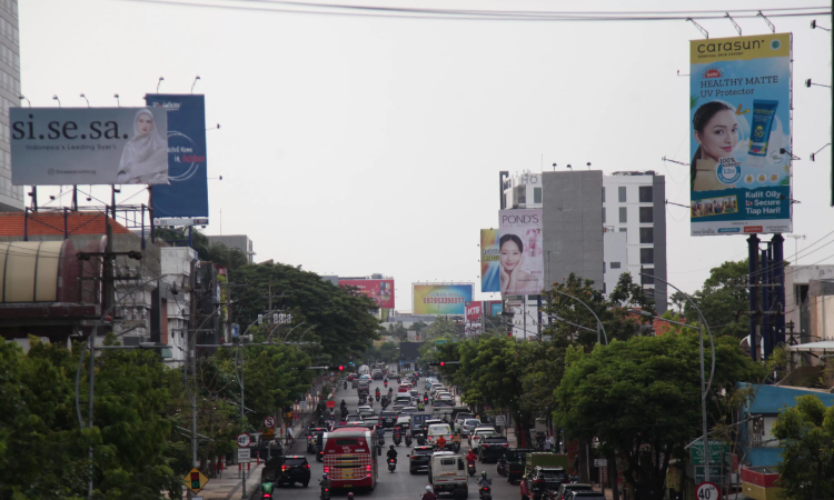 Pengendara kendaraan bermotor melintas tak jauh dari papan reklame di Jalan Embong Malang, Surabaya. (Suryanto/Radar Surabaya) - Image