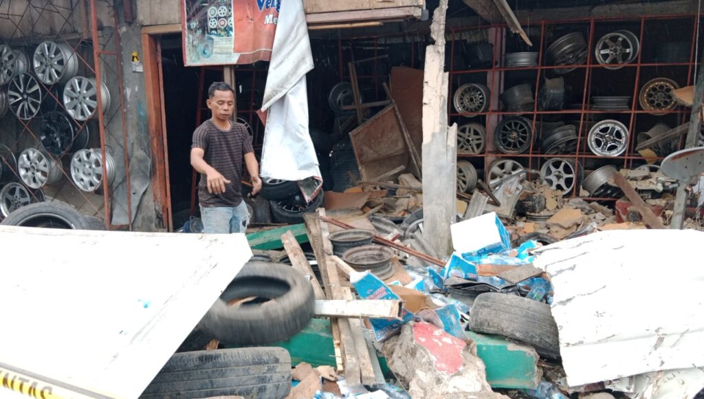 Yasril memperlihatkan bengkel ban miliknya yang rusak parah akibat kecelakaan beruntun di Puncak Bogor pada Selasa (23/1) siang. - Image