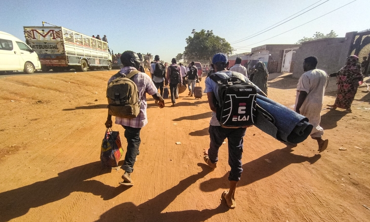Pengungsi akibat konflik di Sudan berjalan dengan barang miliknya di sepanjang jalan di Wad Madani, ibu kota negara bagian al-Jazirah (16/12/2023). (sumber: AFP melalui Getty Images) - Image