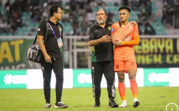 Penjaga gawang Persebaya Ernando Ari Sutaryadi (kanan) didampingi pelatih kiper Benyamin Van Breukelen (tengah) usai pertandingan melawan Bhayangkara Presisi FC di Stadion GBT Surabaya, Minggu (4/2). - Image