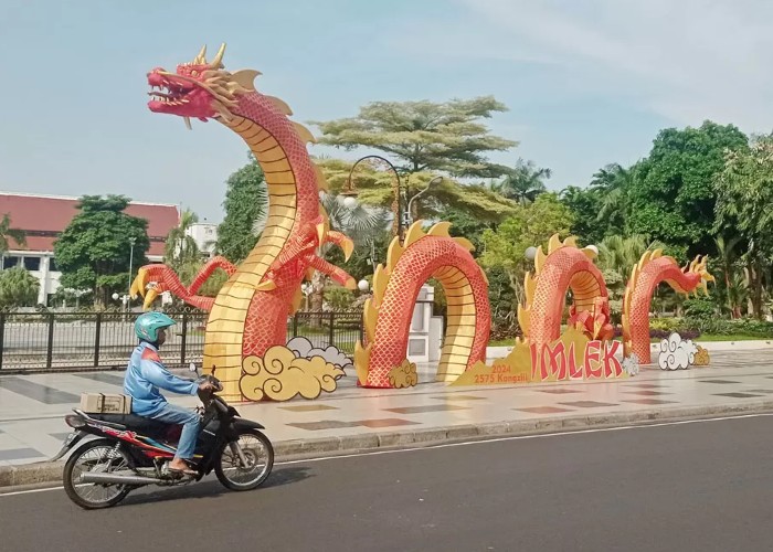 SAMBUT IMLEK: Pengendara kendaraan bermotor melintas tak jauh dari ornamen Naga untuk menyambut Tahun Baru Imlek yang terpasang didepan Balaikota Surabaya, Kamis (8/2). (FOTO: SURYANTO/RADAR SURABAYA) - Image