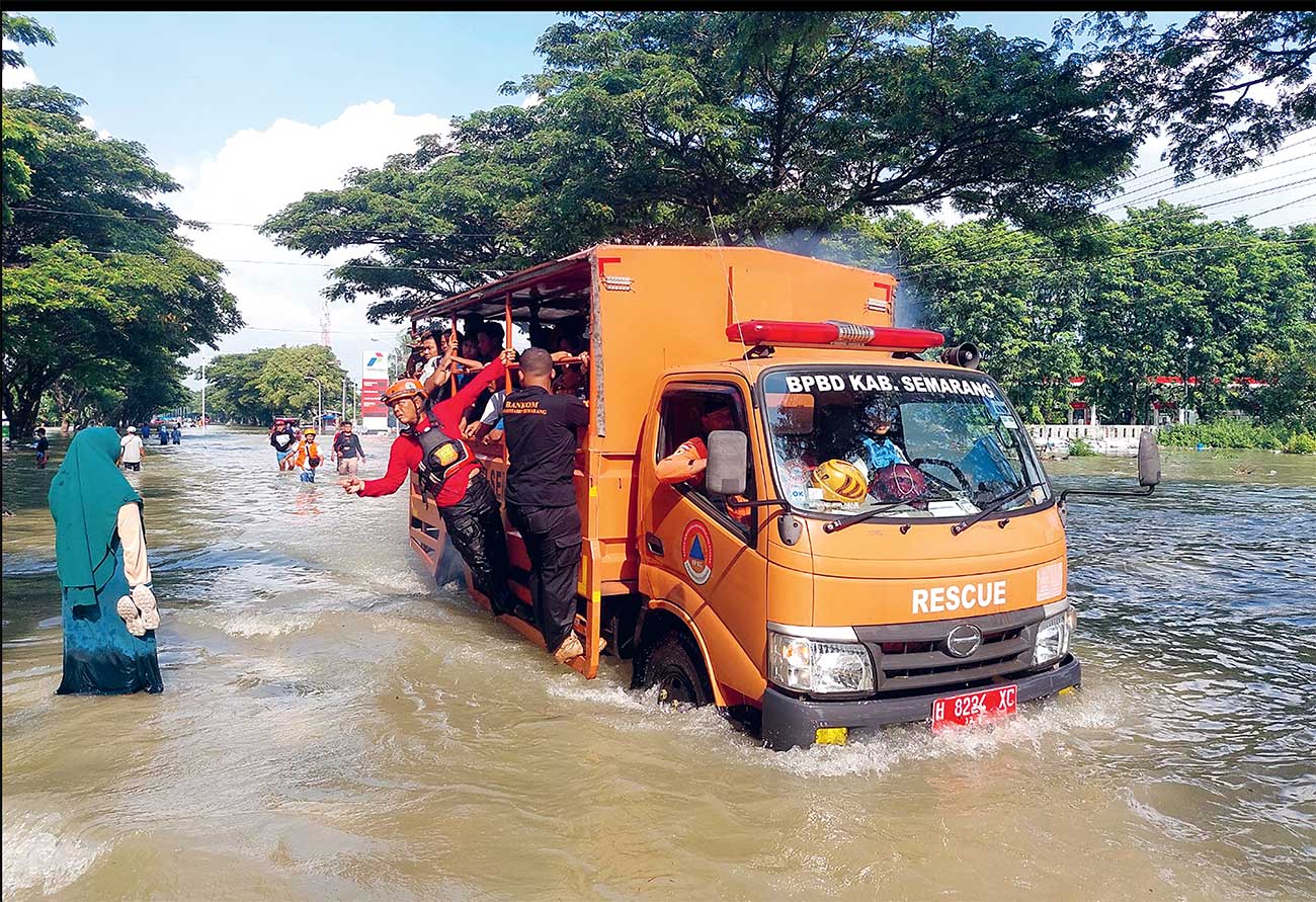 TANGGUL JEBOL: Petugas gabungan berupaya mengevakuasi warga di jalan pantura, Karanganyar, yang masih terendam air kemarin (9/2). - Image