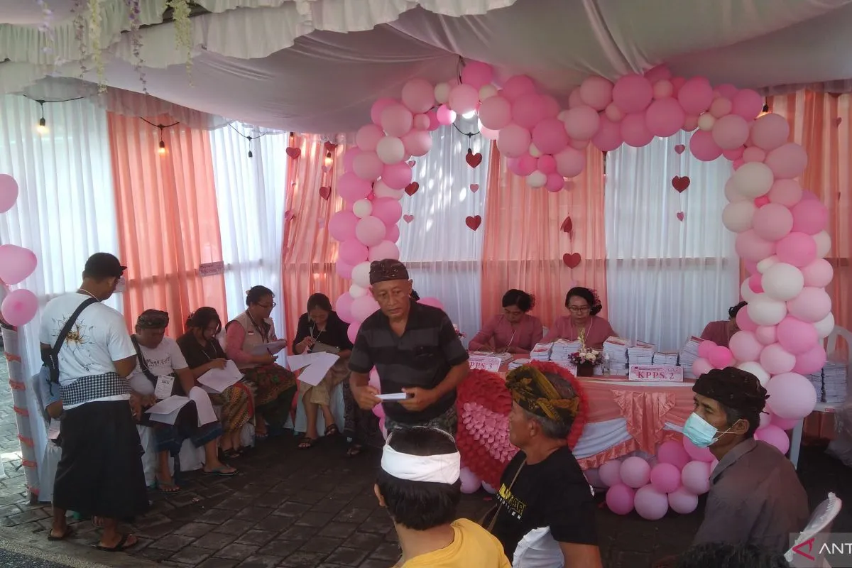 Seorang pemilih bersiap menyalurkan hak suaranya di TPS 026 dengan nuansa adat Bali dikombinasi dengan dekorasi khas kasih sayang atau valentine. (ANTARA/Dewa Ketut Sudiarta Wiguna) - Image