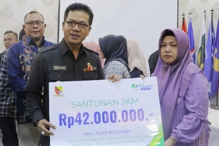Bupati Bandung Dadang Supriatna (kiri) menyerahkan santunan kepada ahli waris petugas pemilu yang meninggal saat bertugas di Kabupaten Bandung, Rabu (21/2). - Image