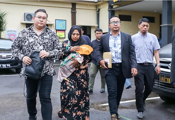 Suyanti, 38, (jilbab hitam) didampingi tim kuasa hukum dari Hotman Paris Hutapea meninggalkan Satreskrim Polres Kediri Kota. - Image