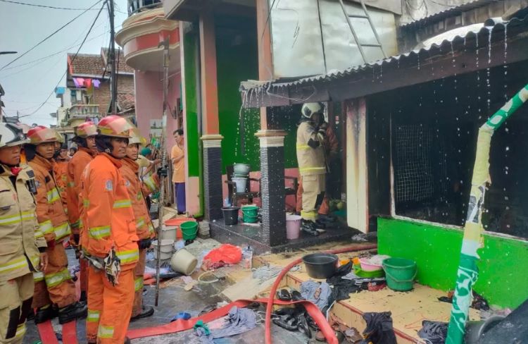 Petugas melakukan pembasahan rumah yang terbakar di Krembangan Jaya Utara, Surabaya. - Image
