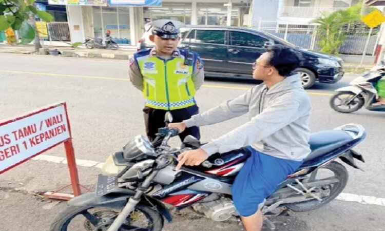 Pemberian teguran secara simpatik oleh petugas Satlantas Polres Malang kepada pengendara yang kedapatan tidak mengenakan helm di Jalan Kawi, Kepanjen. / - Image