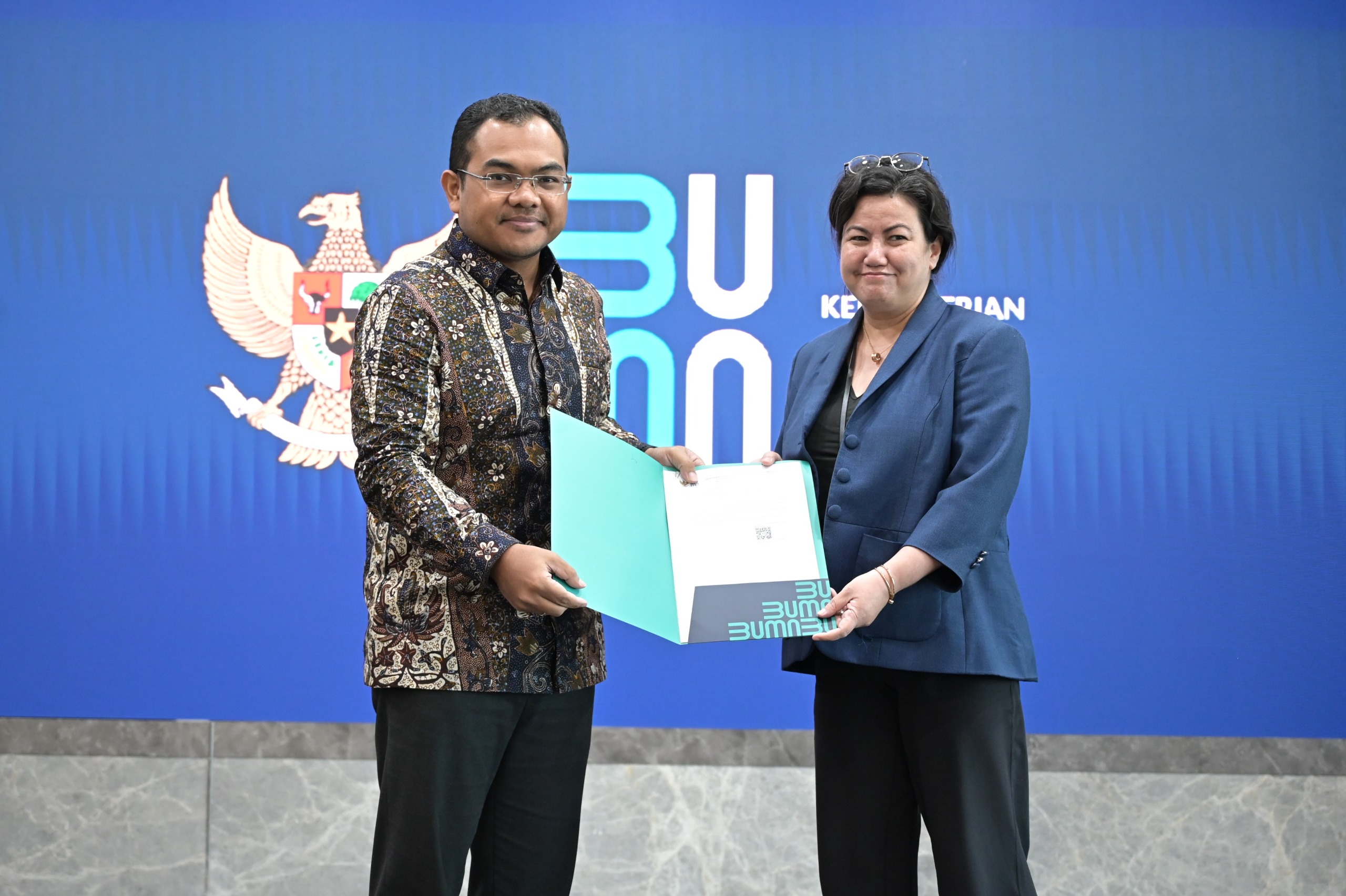 Deputi Bidang Manajemen Sumber Daya Manusia, Teknologi, dan Informasi Kementerian BUMN Tedi Bharata (kiri) saat menyerahkan keputusan Rapat Umum Pemegang Saham pengangkatan Nawal Nely (kanan). - Image