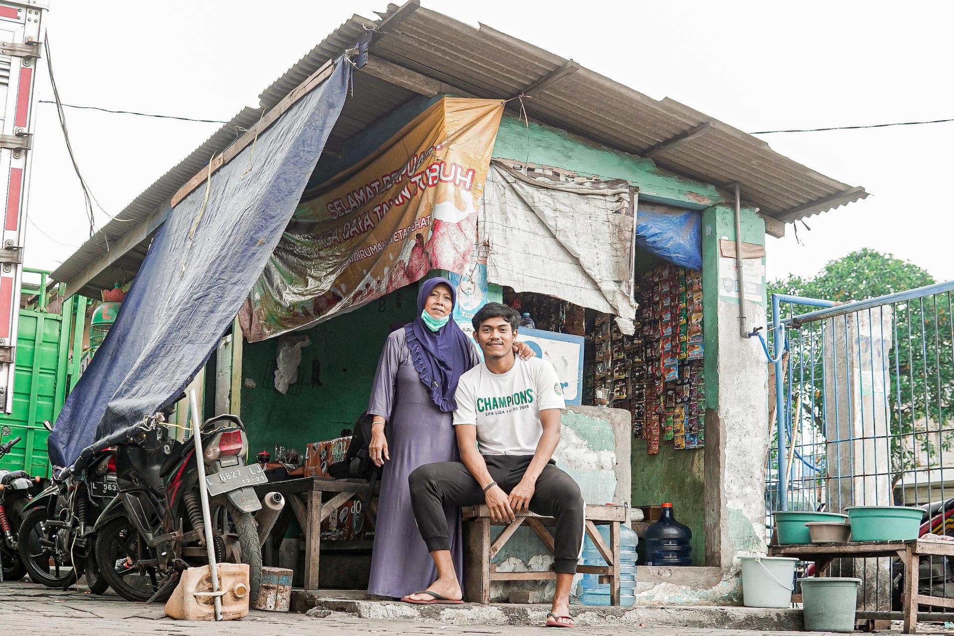 Andhika Ramadhani berfoto bersama sang ibu di depan warung yang terletak di daerah Surabaya Utara. - Image