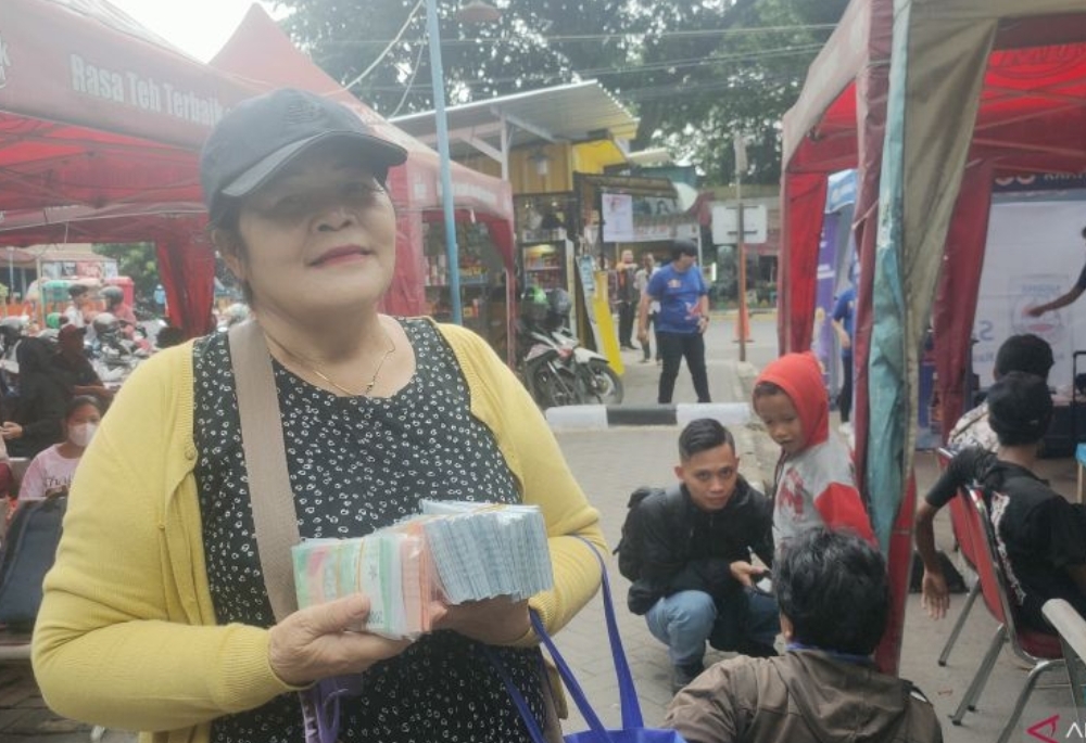 Lamriah (57) seorang penyedia Jasa penukaran uang baru di Terminal Kalideres saat ditemui pada Rabu (3/4/2024). - Image
