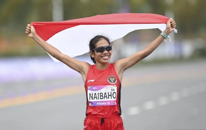 Pelari Indonesia Odekta Elvina Naibaho mengibarkan bendera Merah Putih usai melewati garis finis pada final marathon putri Asian Games 2022 di Qiantang River Green Belt, Hangzhou, Tiongkok. - Image