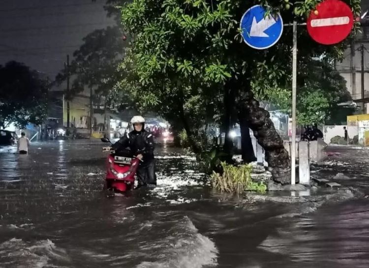 Seorang pria menuntun motornya yang terjebak banjir akibat hujan deras di Kawasan Simo Kalangan, Surabaya, Kamis malam (4/4) - Image