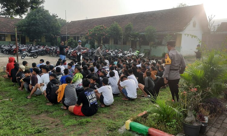 Petugas kepolisian dari Polres Mojokerto sedang melakukan pembinaan kepada para pebalap liar yang terjaring patrol di Jalan Desa Kedunguneng, Kecamatan Bangsal, Kabupaten Mojokerto. (Radar Mojokerto) - Image