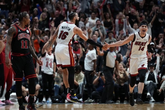 Pemain Miami Heat Tyler Herro (kanan) merayakan tripoin yang dibuatnya bersama Caleb Martin (tengah) saat timnya melawan Chicago Bulls pada babak play-in di Kaseya Center Miami, Florida. - Image